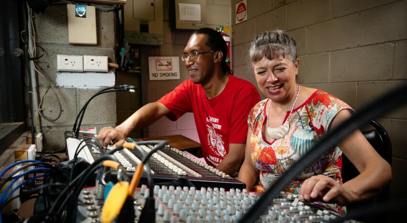 Two people working at an lightning / audio board.