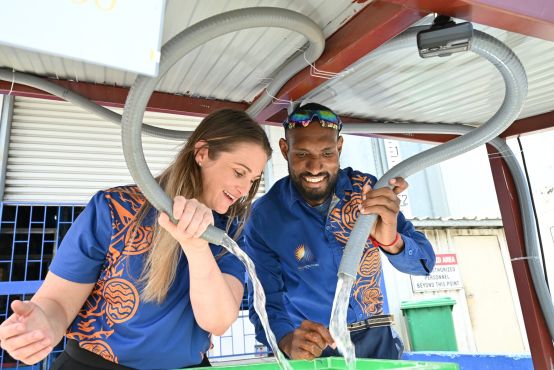 A lady and a man are smiling while working together with a water pipe