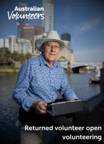 The cover page of the linked document. It includes the Australian Volunteers logo, and the title of the document: 'Returned volunteer open volunteering'. The background image is of man looking directly into the camera with a mobile tablet device on his lap.