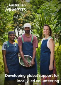 The cover page of the linked document. It includes the Australian Volunteers logo, and the title of the document: 'Developing global support for locally led volunteering'. The background image is of three people standing outdoors wearing aprons. One person holds a metal bowl containing green leaves.