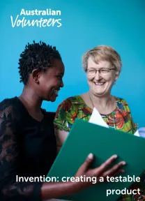 The cover page of the linked document. It includes the Australian Volunteers logo, and the title of the document: 'Invention: creating a testable product'. The background image is of two people smiling in conversation with each other. One person holds a binder of papers open between them.