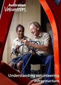 The cover page of the linked document. It includes the Australian Volunteers logo, and the title of the document: 'Understanding volunteering infrastructure'. The background image is of two people in conversation as they sit in front of machinery.